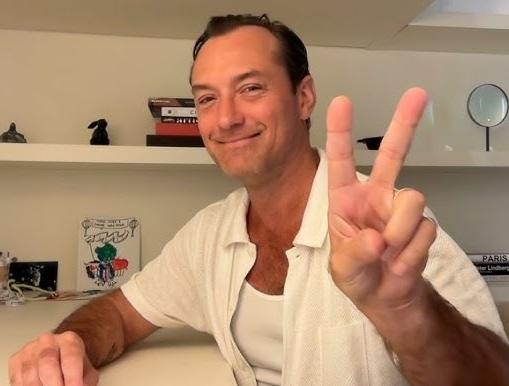 Jude Law na scenie teatralnej, oświetlony światłami reflektorów, w trakcie intensywnego występu.