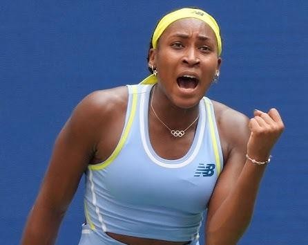 Coco Gauff na korcie tenisowym, skupiona i zdeterminowana, z rakietą w dłoni, gotowa do akcji.