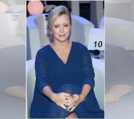 Agnieszka Wagner przeglądająca swój profil na Instagramie na telefonie, z delikatnym uśmiechem, w tle nowoczesne wnętrze.