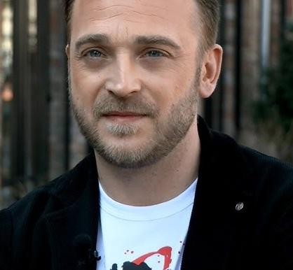 Mateusz Gessler, kucharz i restaurator, w kuchni, prezentujący swoje umiejętności kulinarne.