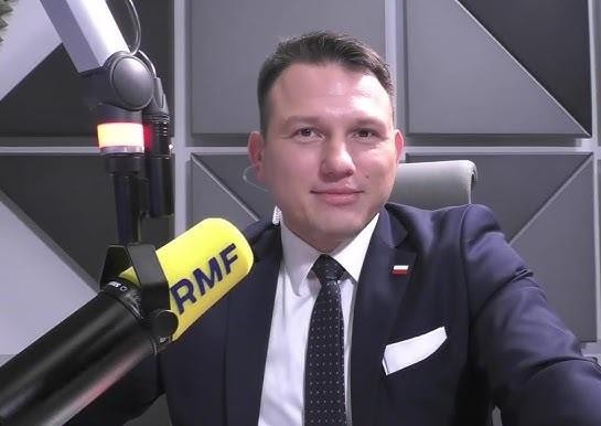 Sławomir Mentzen przemawiający z pasją na wiecu politycznym, z tłumem zwolenników w tle.