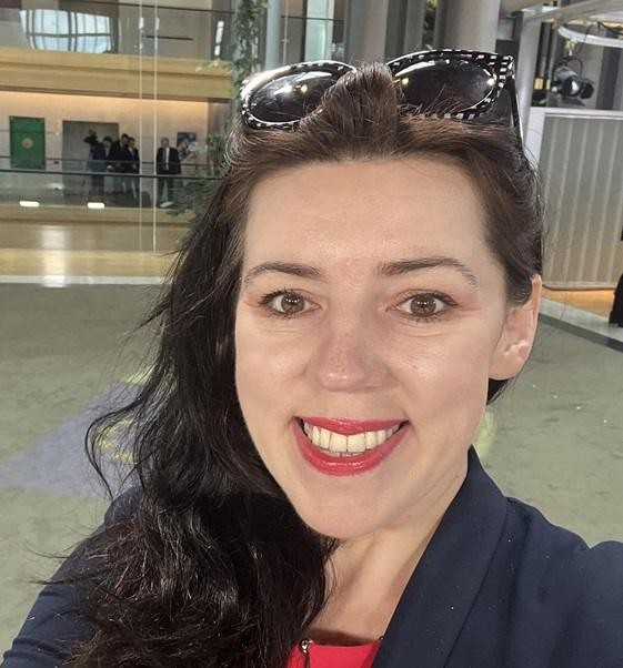 Dominika Ćosić jako korespondentka w Brukseli, aktywnie uczestnicząca w wydarzeniach politycznych, z mikrofonem w ręku lub w tle budynku Parlamentu Europejskiego.