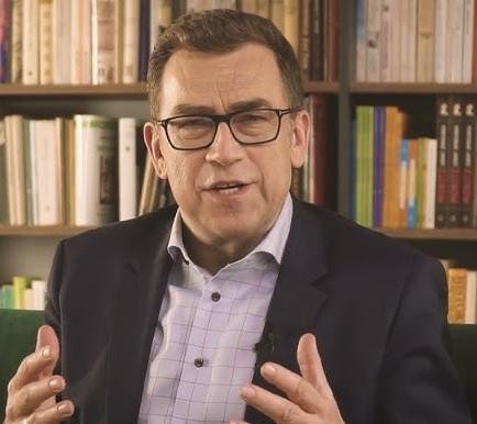 Maciej Orłoś prowadzący szkolenie z wystąpień publicznych, uśmiechnięty i gestykulujący.
