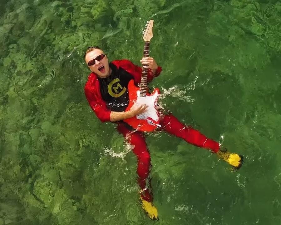 Czadoman (Paweł Dudek) podczas energicznego występu na scenie, otoczony światłami koncertowymi i entuzjastyczną publicznością.