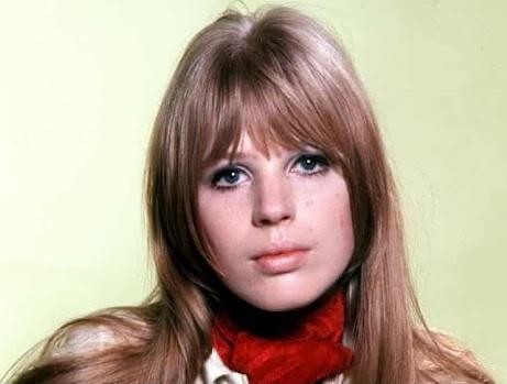 Dynamiczne czarno-białe zdjęcie Marianne Faithfull występującej na scenie w późnych latach 70., oddające jej energię i intensywność, z mikrofonem w dłoni i emocjonalnym wyrazem twarzy.